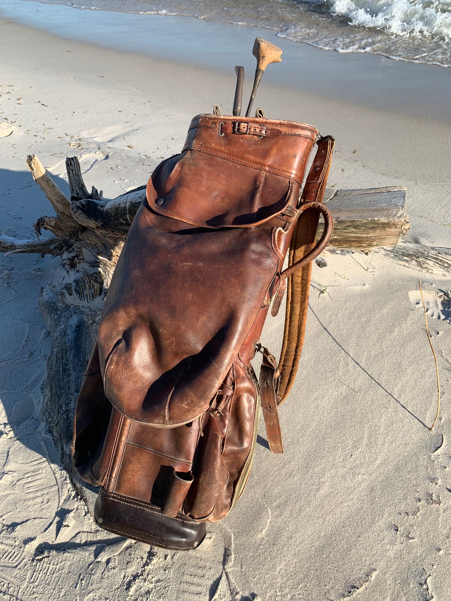 Gammel golfbag i læder med to gamle køller