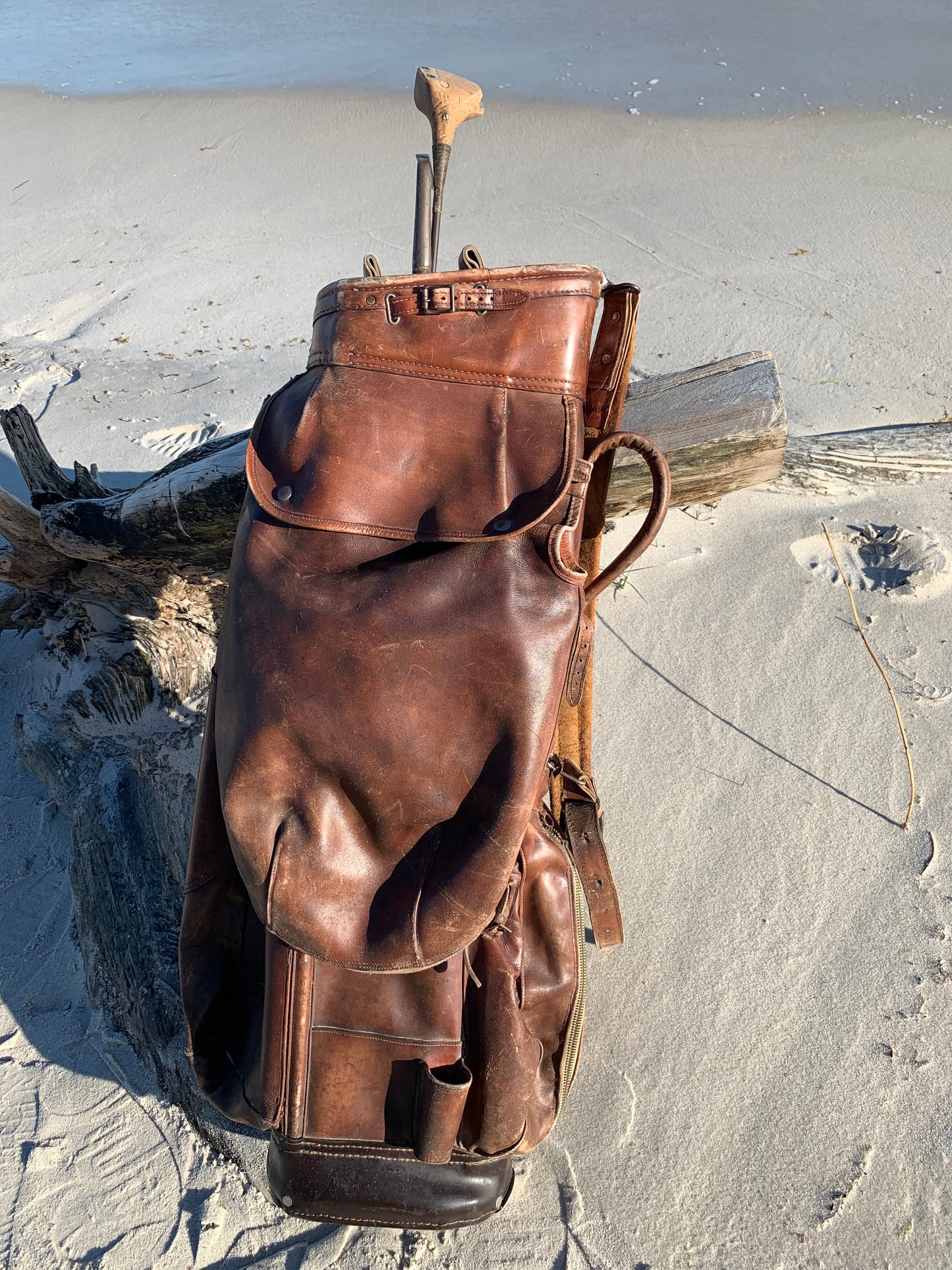 Gammel golfbag i læder med to gamle køller