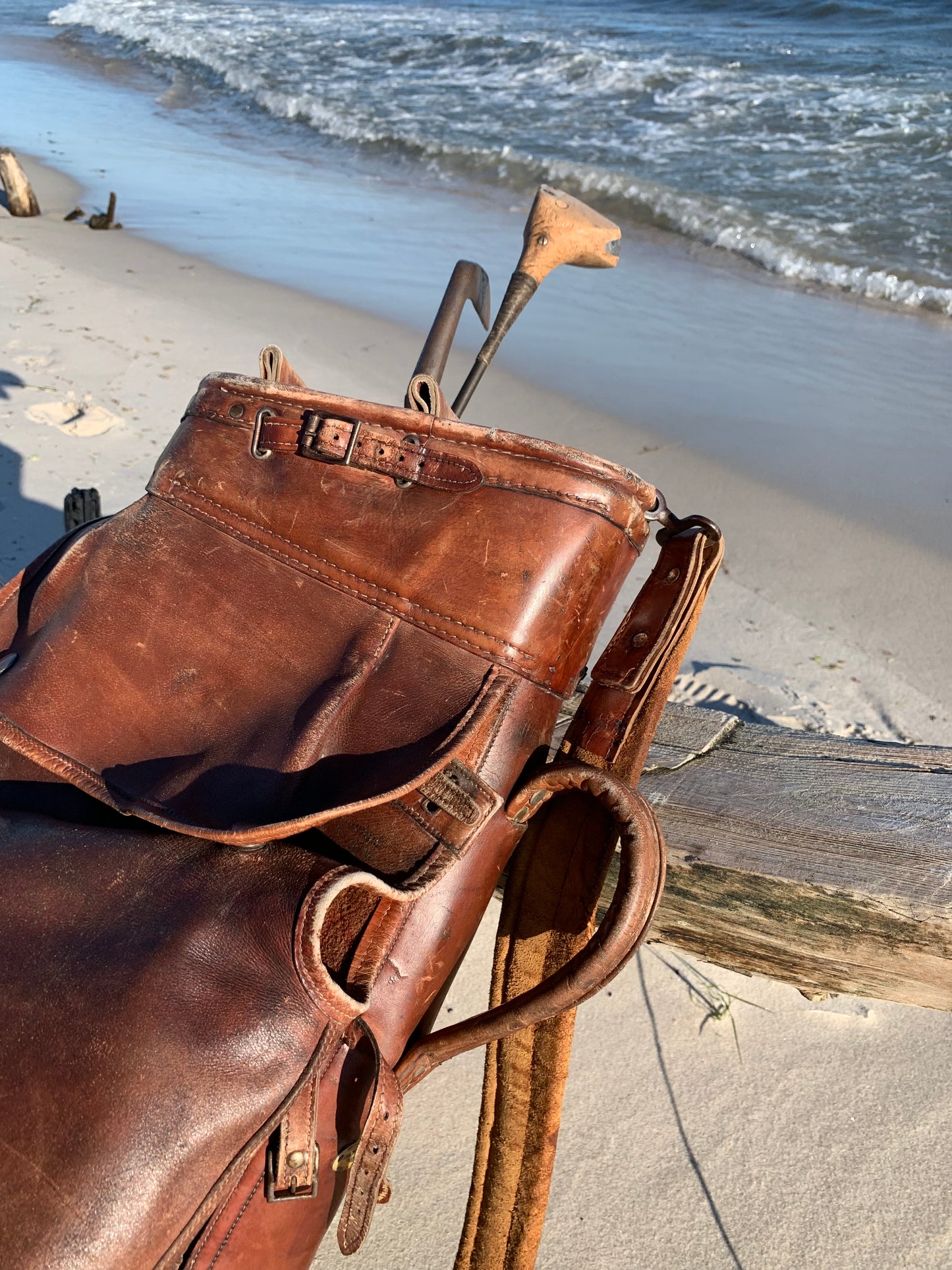 Gammel golfbag i læder med to gamle køller